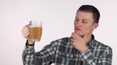 Yakışıklı bir genç adam, şık bir ekose gömlek giymiş, köpüklü bir bira bardağını incelerken düşünceli bir şekilde çenesini ovuyor. Dalgın bakışları ve altın sıvı bir anlık kalite değerlendirmesini yansıtıyor. El sanatları bira takdir ruhunu somutlaştırıyor.