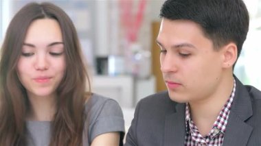 Yakın çekim genç ve çekici bir çifti yakalıyor. Bir iş danışmanlığı yapıyor, profesyonellik ve yaratıcılık yayıyor. Odaklanmış ifadeleri ve şık kıyafetleri dinamik bir ortaklığı yansıtıyor, parlak bir fikir üzerine beyin fırtınası yapıyorlar.