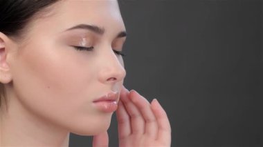 Çekici esmer bir kadın yan bir görüntüde, parmaklarıyla nazikçe şakağını okşuyor. Bu güzel Asyalı model, gözleri kapalı, huzur ve zarafet saçıyor, özgüven ve güzellik dolu bir anı somutlaştırıyor.
