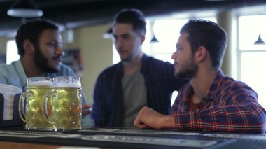 Canlı bir barda toplanan üç neşeli adam, buzlu bardaklarını kaldırıp kadeh kaldırarak takımlarının zaferinin heyecanıyla eğleniyorlar. Atmosfer heyecan verici, kahkaha ve dostluk dolu hikayelerini paylaşıyorlar ve anın tadını çıkarıyorlar.