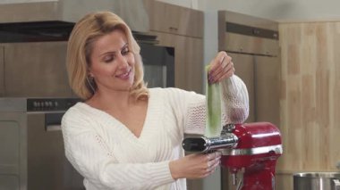 Işıl ışıl, olgun bir kadın, modern mutfağında parlak bir makarna makinesi kullanarak canlı yeşil makarna hamurunu ustalıkla dağıtırken neşeyle ışıldıyor. Bu nefis sahne aşçılık geleneğinin özünü yakalıyor, taze yemek yapma tutkusunu sergiliyor.