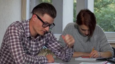 Yakışıklı genç bir adam, gözle görülür şekilde yorgun, parlak bir kampüs kütüphanesinde özenle çalışırken gözlüğünü çıkarıyor. Notlar ve ders kitaplarıyla çevrelenmiş, sınavlara hazırlanan öğrencilerin mücadelesini ve kararlılığını somutlaştırıyor,