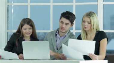 Genç profesyonellerden oluşan dinamik bir üçlü, bir erkek ve iki kadın, belgeleri incelerken ve dizüstü bilgisayarda yazarken ortak bir tartışmaya girişirler. Onların odaklanmış ifadeleri ve takım çalışması parlak bir yenilik ve üretkenlik ortamı yaratır.