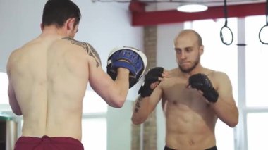Canlı bir spor salonu ortamında, güçlü bir genç adam hem kararlılık hem de odaklanmayla antrenman yaparken boks yeteneklerini sergiliyor. Eğitimlerinin yoğunluğu enerji yayıyor, profesyonel sporların özünü vurguluyor ve