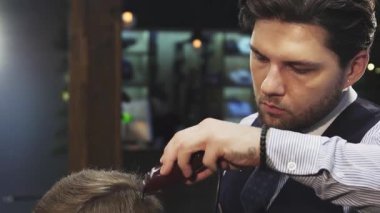 Şık bir berber, odaklanmış ve becerikli, şık bir berber dükkanında müşterilerinin saçlarını titizlikle buduyor. Yumuşak ışıklandırma ve klasik dekor ile vurgulanan ılık ortam, tımar ve stil deneyimini geliştirir, sanatın sanatını gözler önüne serer