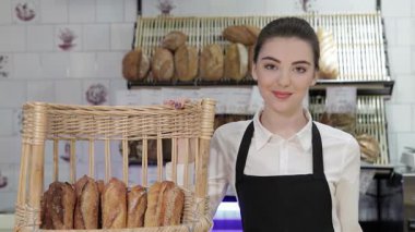 Neşeli genç bir fırıncı kız fırınında gururla duruyor ve içi taze pişmiş ekmekle dolu bir sepeti sergiliyor. Sıcak hamur işlerinin davetkar aroması havayı dolduruyor, müşterileri bu zevki tatmaya çağıran hoş bir atmosfer yaratıyor.