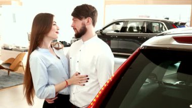 Şık bir çift, galeride parlak siyah bir SUV 'nin yanında sıcak bir kucaklaşmayı paylaşıyor, mutluluk ve heyecan saçıyor. Esmer adam gururla arabanın anahtarını tutarken zarif kız arkadaşı ona bakıyor, aşkını ve paylaştığı macerayı gösteriyor.