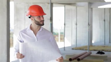 Turuncu bir şapka takan genç bir Kafkasyalı mimar, inşaat halindeki bir binanın planlarını dikkatle inceliyor. Beton duvarlar ve iskelelerle çevrelenmiş, yenilik ruhunu ve hareketli inşaattaki ilerlemeyi somutlaştırıyor.