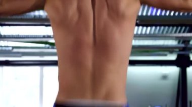 Kararlı bir Kafkas atleti barfiks çekerken gücünü sergiliyor, kaslı sırtı belirgin bir şekilde sergileniyor. Spor salonları atmosferi canlandırıyor. Forma ve fiziksel maharete olan bağlılığını vurguluyor.