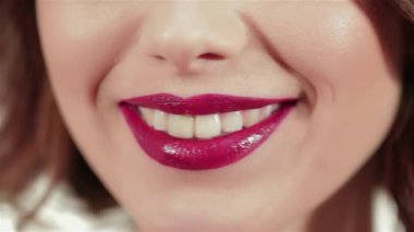 Bu çarpıcı yakın plan, güzel genç bir kadının parlak, parlak bir rujla süslenmiş, ışıl ışıl dudaklarını yakalar. Kusursuz cildine ve makyajının yumuşak ışıltısına odaklanması davetkar bir atmosfer yaratıyor.