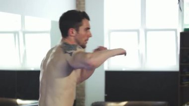 Odaklanmış genç, kaslı bir erkek boksör, iyi aydınlatılmış bir spor salonunda güçlü yumruklar atıyor ve kendini adamışlığını ve atletizmini sergiliyor. Kolundaki vurucu dövme, yoğun antrenmanına, bir şampiyonun ruhunu somutlaştıran sert bir kenar ekliyor.