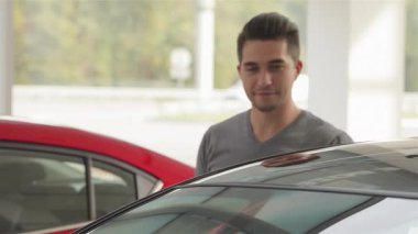 Neşeli genç bir adam, gösterişli bir arabaya yaslanır. Memnuniyet ve heyecan saçan bir jest yapar. Bu canlı sahne başarılı bir araba alımının özünü yakalıyor, modern bir araçta mükemmel bir araç bulmanın sevincini gösteriyor.