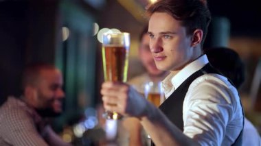 Dört başarılı iş adamından oluşan canlı bir grup soğuk bira bardaklarıyla tezahürat yapıyor, canlı bir barda tutkulu bir şekilde futbol izlerken kahkahaları yankılanıyor. Atmosfer heyecan dolu, yoldaşlık ve heyecanla dolu.