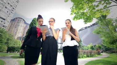 Üç dinamik iş kadını, şık resmi kıyafetler giyiyorlar, açık havada işbirliği yapıyorlar, özgüven ve profesyonellik yayıyorlar. Çekici gülümsemeleri ve odaklanmış ifadeleri, şehir ortamında canlı bir başarı ve takım çalışması atmosferini yansıtıyor.