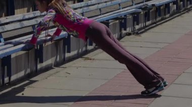 Kararlı genç bir kız stadyumda enerjik bir şekilde jimnastik yapıyor, atletizmini ve dikkatini gösteriyor. Hareketli egzersiz kıyafetleri içinde öne doğru eğiliyor, gücünü ve bağlılığını mavi bir zemine karşı gösteriyor.