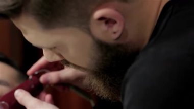 Modayı takip eden bir berber dükkanında, yetenekli bir berber, sakalını titizlikle tıraş eder, titiz ve dikkatli davranır. Zengin ahşap tonlar ve klasik dekor ile vurgulanan ılık ortam, tımar deneyimini güçlendirir ve onu bir anlık