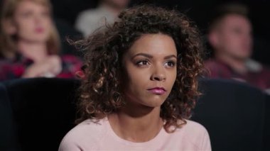 Kıvırcık saçlı güzel bir kız korku filmine dalmış durumda. Yüzündeki ifade şüphe ve entrikayı yansıtıyor. Sıcak bir tiyatroda arkadaşlarla çevrili olan atmosfer, patlamış mısır ve içecekleri paylaşırken heyecanla uğulduyor.