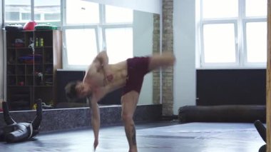 Kaslı bir MMA dövüşçüsü atletik hünerini sergilerken çarpıcı bir yüksek tekme, enerji ve kararlılık sergiliyor. Spor salonları onun eğitiminin yoğunluğunu arttırıyor, disiplin ruhunu somutlaştırıyor.