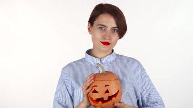 Canlı kırmızı dudakları olan büyüleyici bir kadın şakacı bir şekilde göz kırpıyor, güzel oyulmuş bir Cadılar Bayramı balkabağını sallıyor. Bu şenlik sahnesi sonbahar kutlamalarının özünü yansıtıyor, neşe saçıyor ve ürkütücü bir eğlence hissi veriyor.