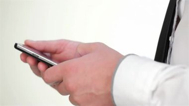 Parlak bir akıllı telefonu kavrayan, profesyonel bir atmosfer sergileyen bir adamın yakın çekim görüntüsü. Görüntü modern iş iletişiminin özünü yakalıyor, teknoloji ve insan duygularının kurumsal bir ortamda karışımını vurguluyor.