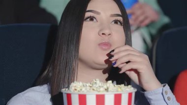 Asyalı bir kız karanlık bir sinemada oturuyor, ekrandaki dramayı izlerken yüzünde endişe dolu bir ifade var. Arkadaşları tarafından çevrelenmiş, patlamış mısır ve gazozdan hoşlanırlar, ortak bir heyecan ve beklenti ortamı yaratırlar.