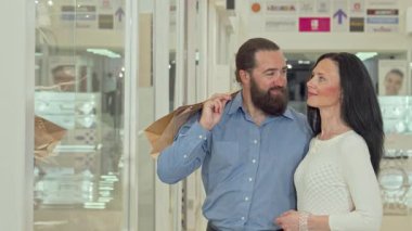 Neşeli, olgun bir çift, canlı bir alışveriş merkezinde bir giyim mağazasının vitrinine hayran oldukları bir anı paylaşıyor. Güzel kadın, alışverişin heyecanı içinde kocasını konuşturur. Aşklarını ve bağlantılarını gösterir.