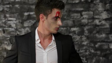 Gösterişli siyah takım elbiseli büyüleyici bir erkek vampir, desenli siyah tuğla bir duvara karşı çarpıcı bir şekilde poz veriyor. Kan kırmızısı aksanlı çarpıcı makyajı, izleyicileri gizemli ve gizemli bir dünyaya davet ederek, Cadılar Bayramı 'nın ürkütücü cazibesini arttırıyor.