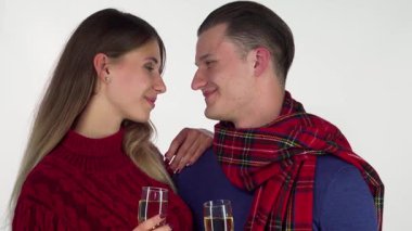 Sıcak kış kıyafetlerine bürünmüş neşeli genç bir çift şampanya kadehleriyle kadeh kaldırırken ışıl ışıl gülümsüyor. Bu festival sahnesi sıcaklık ve neşe saçıyor. Tatil sezonunda aşkı kutlamak için mükemmel.