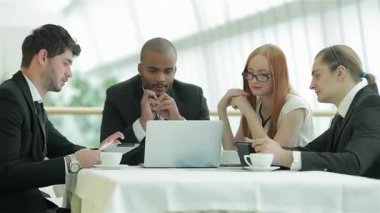 Kendine güvenen dört profesyonelden oluşan bir grup, iki erkek ve iki kadın, gösterişli bir masanın etrafında toplanarak, işbirlikçi bir tartışma içerisindeler. Gülüşleri ve odaklanmış ifadeleri takım çalışmasının ve yeniliğin canlı atmosferini yansıtıyor.