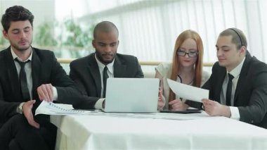 Dört kendinden emin işadamı ve bir iş kadını, çağdaş bir ofis ortamında yapılan verimli bir toplantıda önemli belgeleri incelemeye dalmış durumdalar. Atmosfer takım çalışması ve hırsla donatılmıştır. Aynı anlayış ve stratejileri paylaşıyorlar.