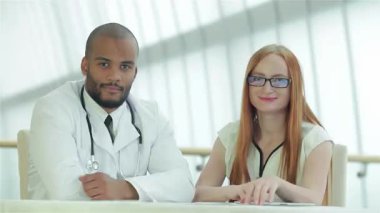 Kendine güvenen bir doktor ve neşeli bir hasta modern bir klinik ortamında pozitif enerji saçan olumlu bir jesti paylaşıyorlar. Gülüşleri başarılı bir istişareyi yansıtıyor, sağlık ve tıbbi bakımda takım çalışmasının önemini vurguluyor.