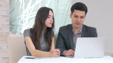 Genç ve dinamik bir iş adamı ve kadın şık bir dizüstü bilgisayardaki verileri analiz ederek canlı bir tartışmaya daldılar. Onların odaklanmış ifadeleri ve işbirlikçi ruhları modern ofis ortamında takım çalışmasının özünü vurgular.