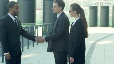 Hareketli bir şehir caddesinde hareketli bir tokalaşmada, şık giyinmiş, güler yüzlü iş adamlarından oluşan dinamik bir üçlü. Bu canlı sahne, işbirliğinin ve başarının özünü yakalıyor ve yeni ortaklıkların heyecanını vurguluyor.