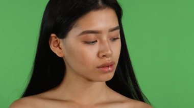 Bu çarpıcı portre çarpıcı bir Asyalı kadının dudağına piercing takıp kameraya bakarken kendine olan güvenini gösteriyor. Parlak yeşil renkli bir arka plana sahip, doğal güzelliği ve bireyselliği içinden parlıyor,