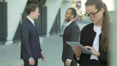 Dengeli bir iş kadını canlı bir şehir caddesinde, iki işadamının sıkı bir tokalaşmasını izleyerek, başarılı bir ortaklığı simgeliyor. Sahne, kentsel zemin ile profesyonellik ve işbirliği gösteriyor