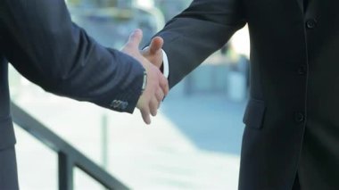 Keskin takım elbiseli iki iş adamının sıkı tokalaşması başarılı bir ortaklığı sembolize ediyor. Parlak kentsel zemin, işbirliği ve karşılıklı başarı atmosferini yükselterek, yeni bir heyecan yaratıyor.