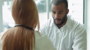 Odaklanmış bir doktor genç bir adamı dikkatlice dinler, parlak bir klinikte sıcak ve destekleyici bir atmosfer yaratır. Doktor, boynunda steteskopla hastanın dinlendiğini ve anladığını hissetmesini sağlarken bir reçete yazar.