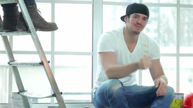 Parlak, havadar bir dairede, neşeli bir ressam bir pencere pervazında oturur, elinde boya fırçası, arkadaşı arka planda bir merdiven tırmanırken. Bu canlı sahne takım çalışmasının ve yaratıcılığın özünü yakalıyor ve ev gelişiminin verdiği hazzı gösteriyor.