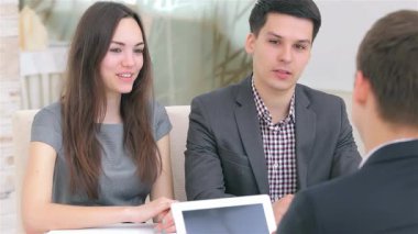 Dinamik genç bir çift şık bir ofis masasında oturan yenilikçi iş projeleri hakkında canlı bir tartışmaya girişiyor. Atmosfer, önlerinde bir tablet ve dizüstü bilgisayarla fikirleri paylaştıkça yaratıcılık ve hırsla doludur.