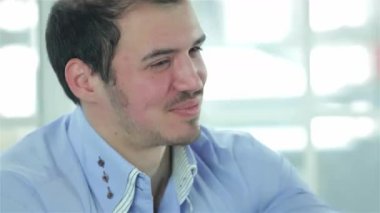 Kendine güvenen mavi gömlekli genç bir iş adamı başarılı bir ortaklığı simgeleyen Afrikalı bir meslektaşıyla sıkı bir tokalaşmayı paylaşıyor. Parlak ofis ortamı profesyonellik ve işbirliği atmosferini güçlendiriyor.