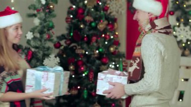 Hoş bir çift, rahat kazaklar ve şen şakrak eşarplar giyiyorlar, güzel paketlenmiş hediyeleri sıcak bir Noel odasında paylaşıyorlar. Sahne ışıl ışıl bir Noel ağacı, yanıp sönen ışıklar ve Noel neşesi ile süslenir.