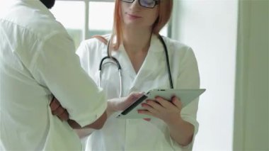 Şefkatli bir doktor anketin sonuçlarını hastayla birlikte bir tablet üzerinde dikkatlice inceleyerek, destekleyici bir atmosferi teşvik eder. Parlak klinik kurulumu, boynundaki steteskopla bir doktor olarak profesyonelliği ve bakımı vurguluyor.