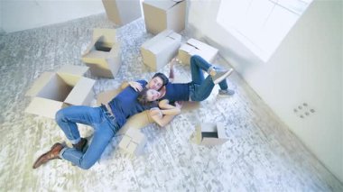 Kutularla dolu, rahat, güneşli bir odada, bir çift yerde sıcak bir kucaklaşma içinde, neşe ve heyecan saçıyor. Kahkahaları boş dairede yankılanıyor. Hayatlarında yeni bir dönemin başlangıcını simgeliyor.