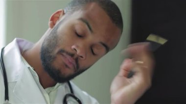 Kendini işine adamış bir doktor modern bir klinikte hastasını dikkatle dinliyor, profesyonelliğini ve şefkatini gösteriyor. Boynunda steteskopla, düşünceli bir şekilde reçete yazıyor, sağlık ve hasta merkezinin özünü somutlaştırıyor.