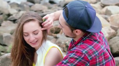 Genç bir adam, arkadaşlarının saçlarını nazikçe tarar. Nehir kenarında, pürüzsüz taşlarla çevrili keyifli bir anı paylaşırlar. Bu hoş sahne, arkadaşlığın, kahkahanın ve kaygısız yaz günlerinin özünü yakalar.