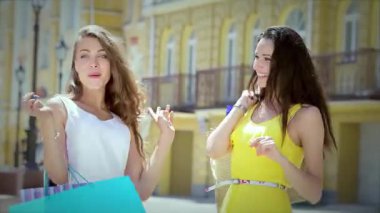 İki genç, modaya uygun kız arkadaş neşeli alışveriş torbalarıyla poz veriyor, neşe saçıyor ve kaygısız bir ruh yayıyorlar. Parlak gülümsemeleri ve hayat dolu enerjileri, dostluğun ve perakendeciliğin özünü yakalamak için mükemmel bir atmosfer yaratıyor.