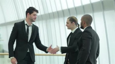 Gösterişli, çağdaş bir ofiste, dört kendine güvenen iş adamı dinamik bir tokalaşma içine girer, başarı ve dostluk yayar. Gülümsemeleri ve resmi kıyafetleri işbirliği ve başarının güçlü bir anını yansıtıyor.