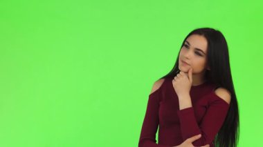 Uzun, dalgalı saçları olan çarpıcı genç bir kadın, parmağını çenesine dayamış, düşünceli bir şekilde uzaklara bakıyor. Canlı yeşil bir arka plana sahip, zarafet ve merakı somutlaştırıyor, izleyicileri hayal gücünün derinliklerini keşfetmeye davet ediyor.