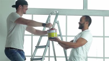 Parlak, havadar bir dairede, genç bir adam merdivendeki arkadaşına neşeyle boya kutusu uzatıyor, takım çalışması sergiliyor. Sahne, ev gelişiminin özünü yakalıyor. Kahkahalar ve arkadaşlıklarla dolu. Dönüşüm için hazırlanıyorlar.