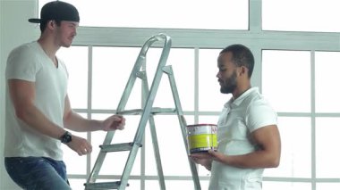 Güneşli, boş bir dairede, iki kendini adamış işçi titizlikle pencereleri ölçüyor ve yeni bir kat tavan boyası için hazırlanıyor. Sahne, sağlam bir merdiven ve canlı boya kovasıyla takım çalışmasının ve işçiliğinin özünü yakalıyor.